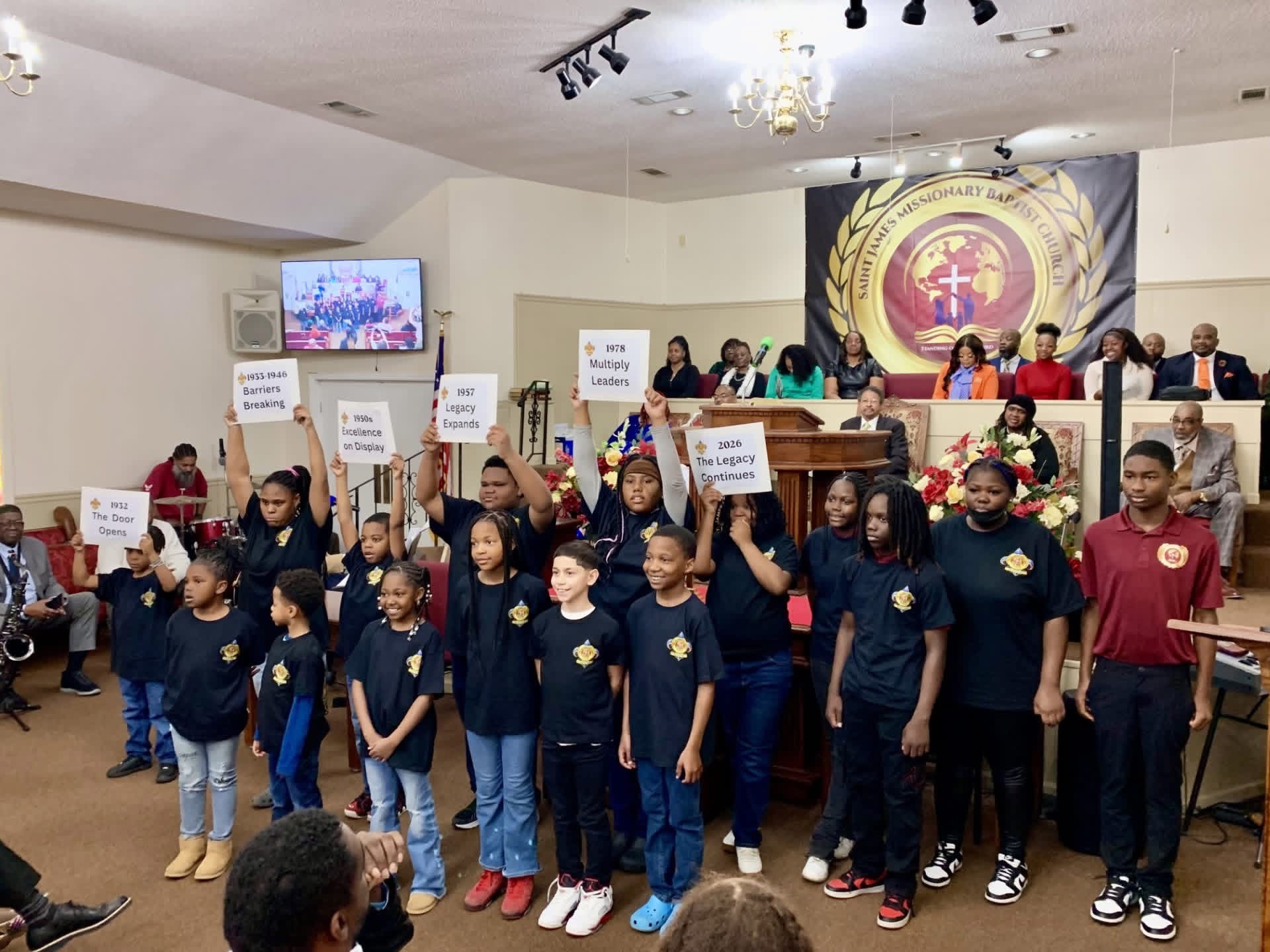 Young people holding milestone signs during a church program