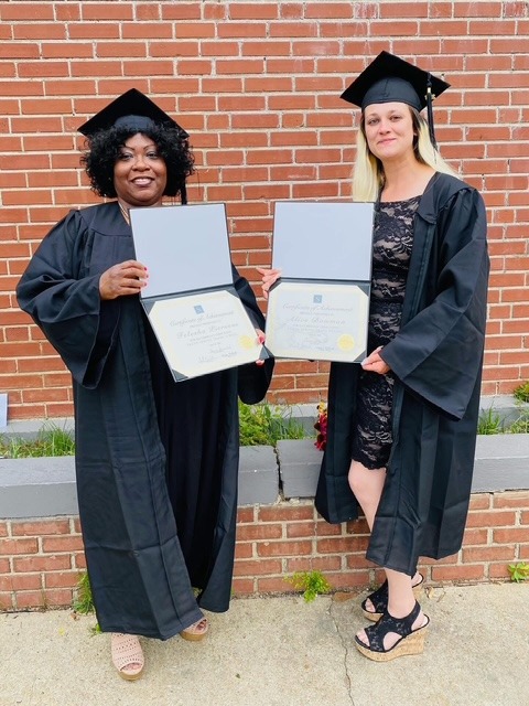 Two adult graduates holding their certificates