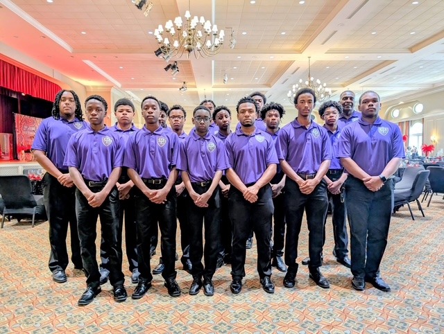 Young men in matching purple shirts standing in a ballroom